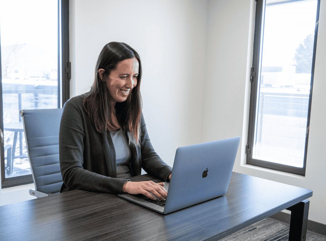 woman sitting at desk on her computer smiling