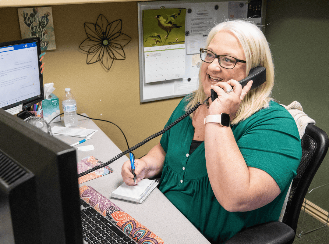 woman sitting at desk on the phone